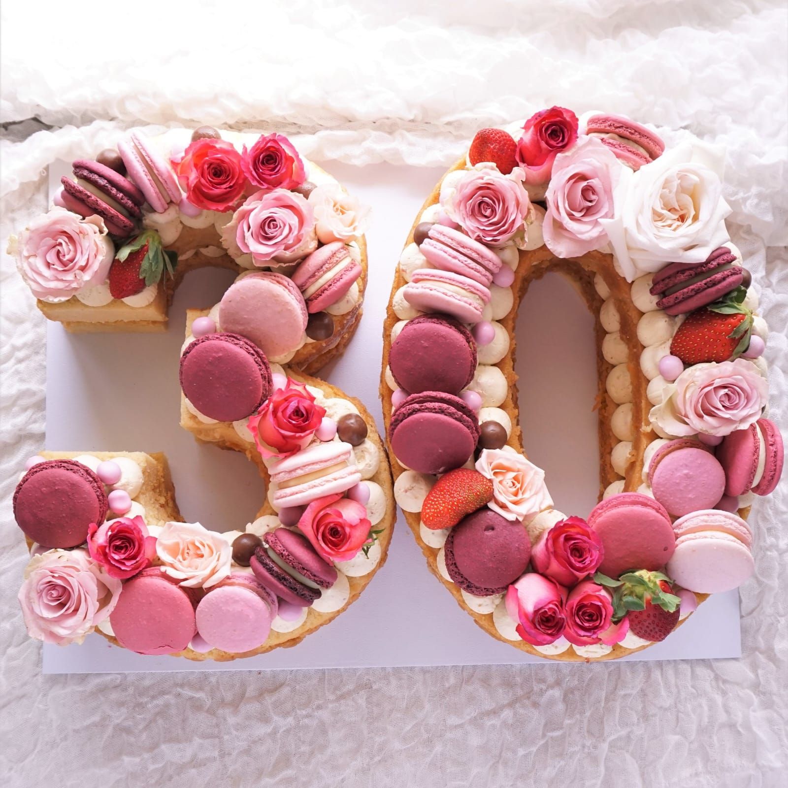 Torta per il 50° compleanno decorata con macarons rosa e rose.