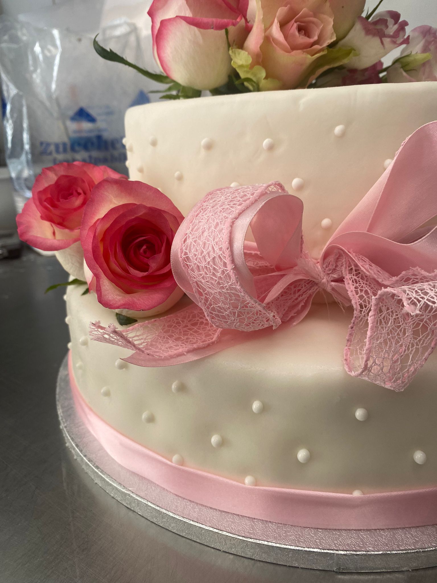 Torta bianca con nastro rosa, rose e pois decorati, ideale per una festa.