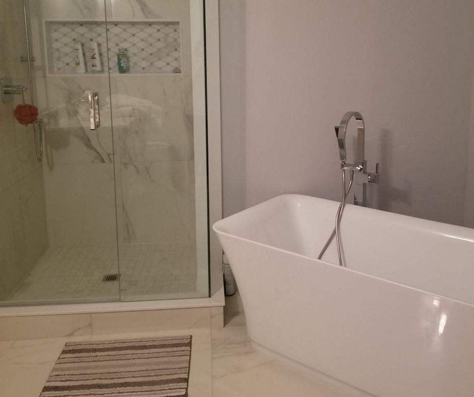 Modern bathroom with a white freestanding bathtub and glass shower.