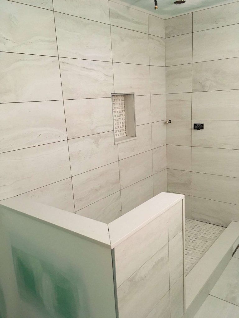 Completed tiled shower with a niche and small curb, neutral color scheme.