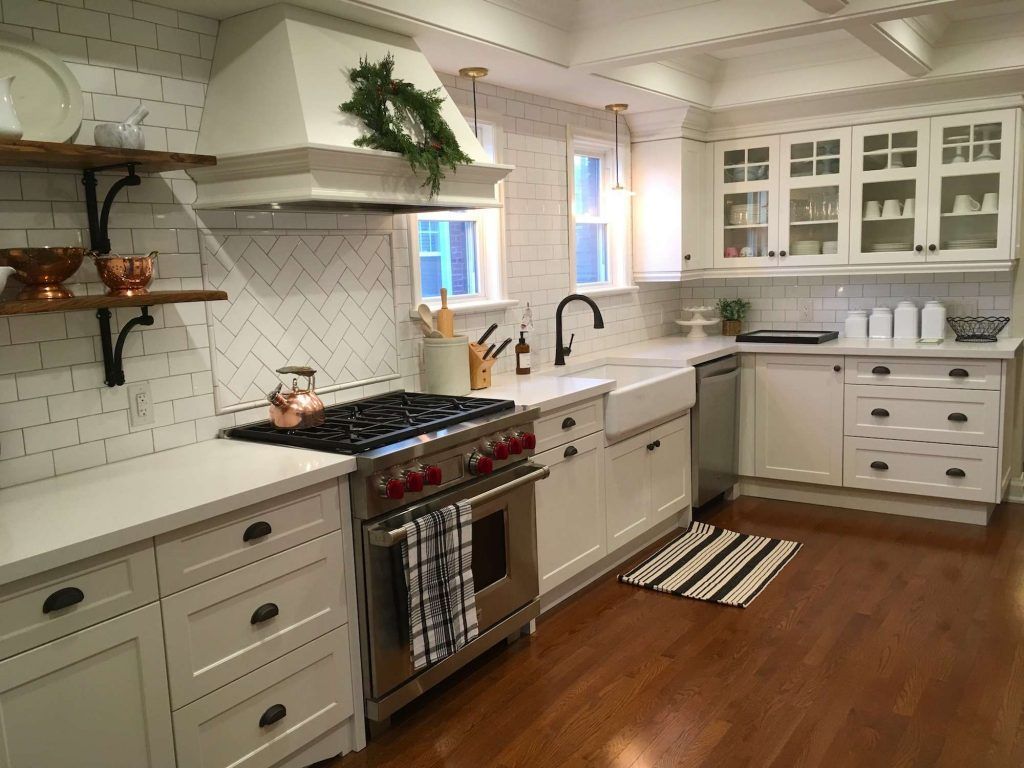 White kitchen with stainless steel appliances, white subway tile backsplash, and wooden shelves.
