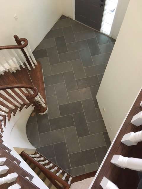 Herringbone pattern dark tile flooring at the bottom of a staircase.