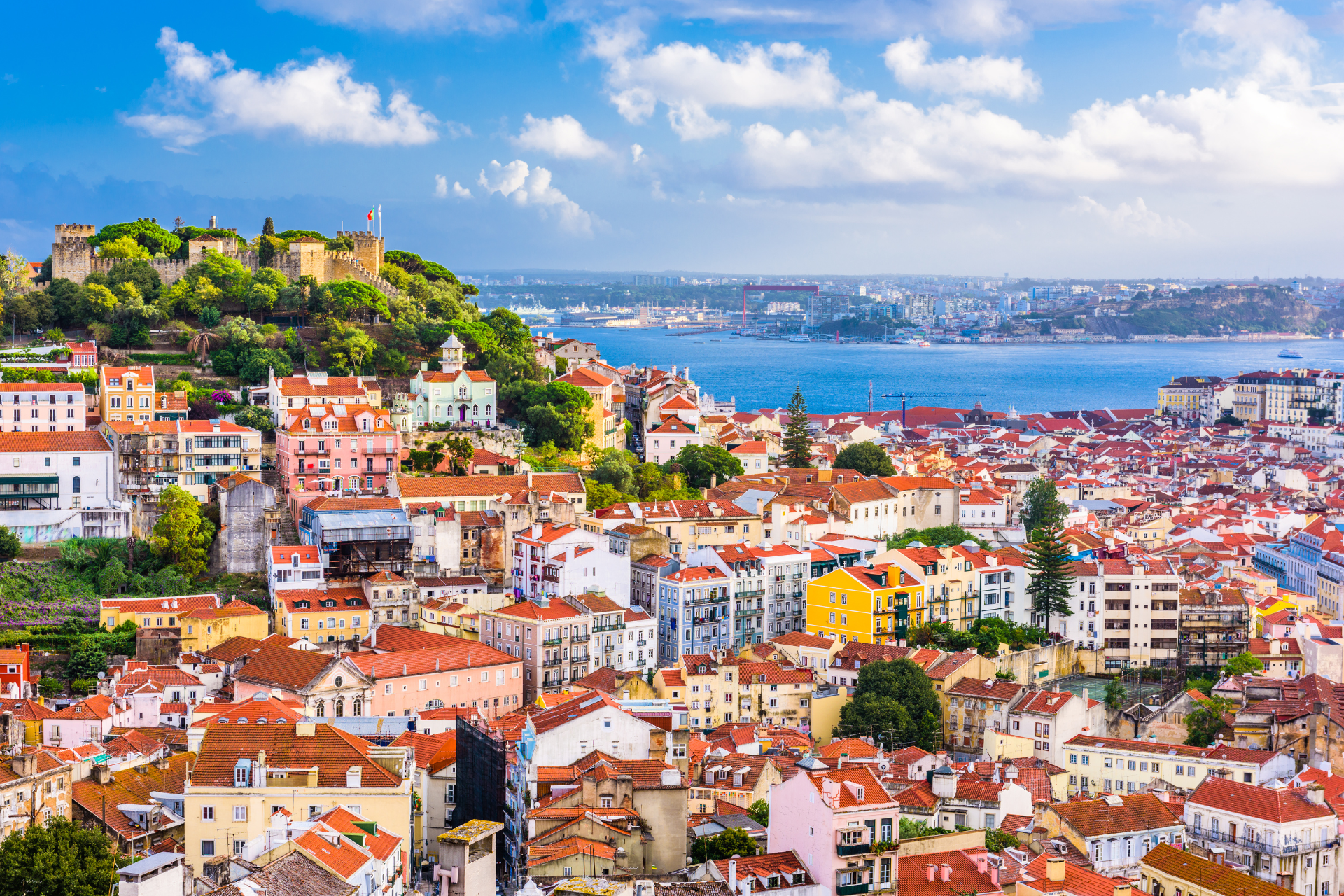 An aerial view of a city with red roofs and a body of water in the background.