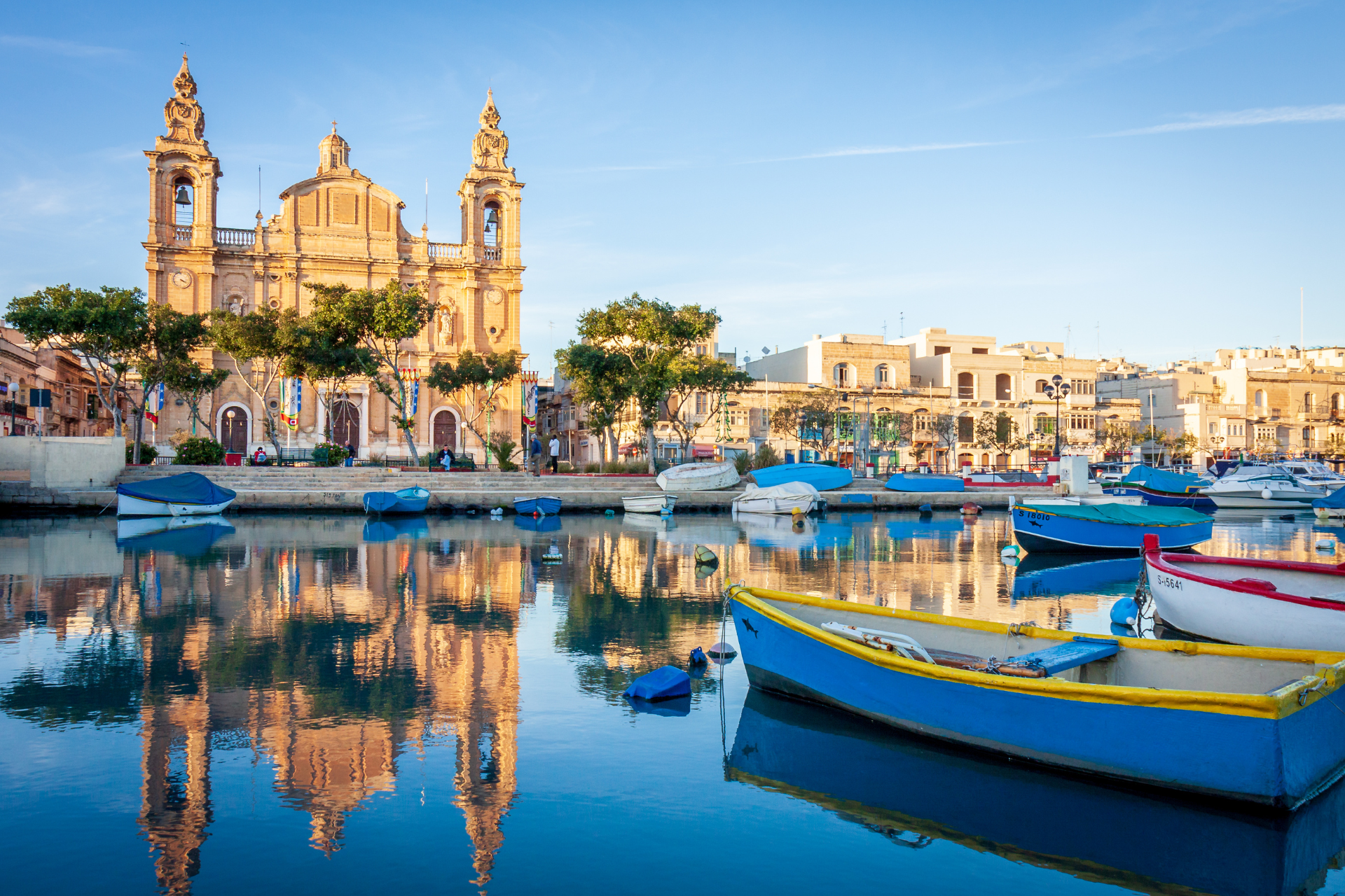 A group of boats are docked in a harbor with a church in the background.