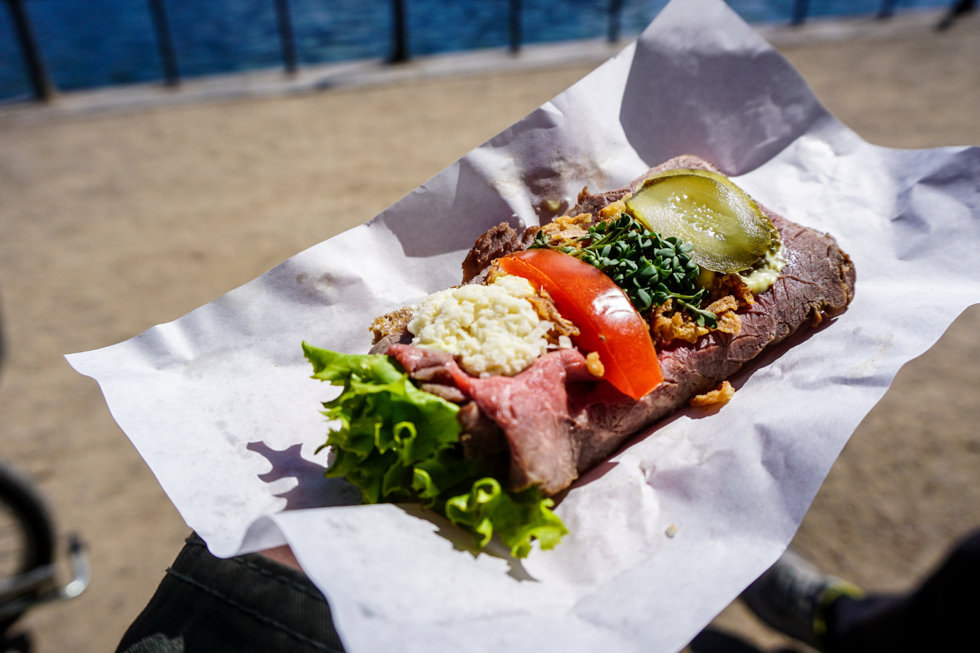 A person is holding a sandwich on a piece of paper.