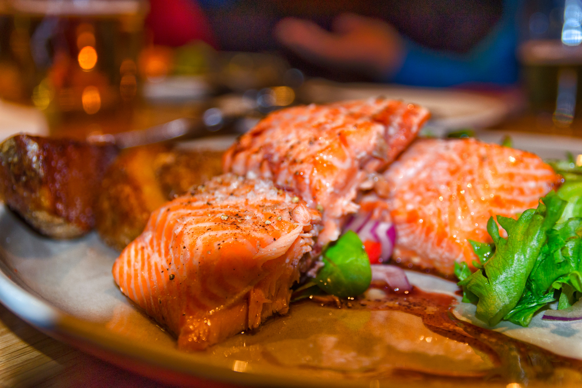 A close up of a plate of food with salmon and vegetables on a table.