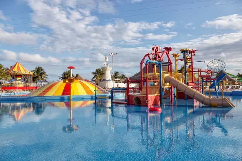 A water park with a swimming pool , slides , and umbrellas.