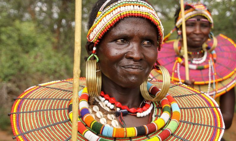 A woman wearing a colorful hat and earrings is smiling.