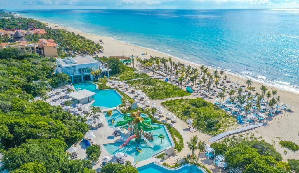 An aerial view of a beach resort with a large pool surrounded by palm trees.