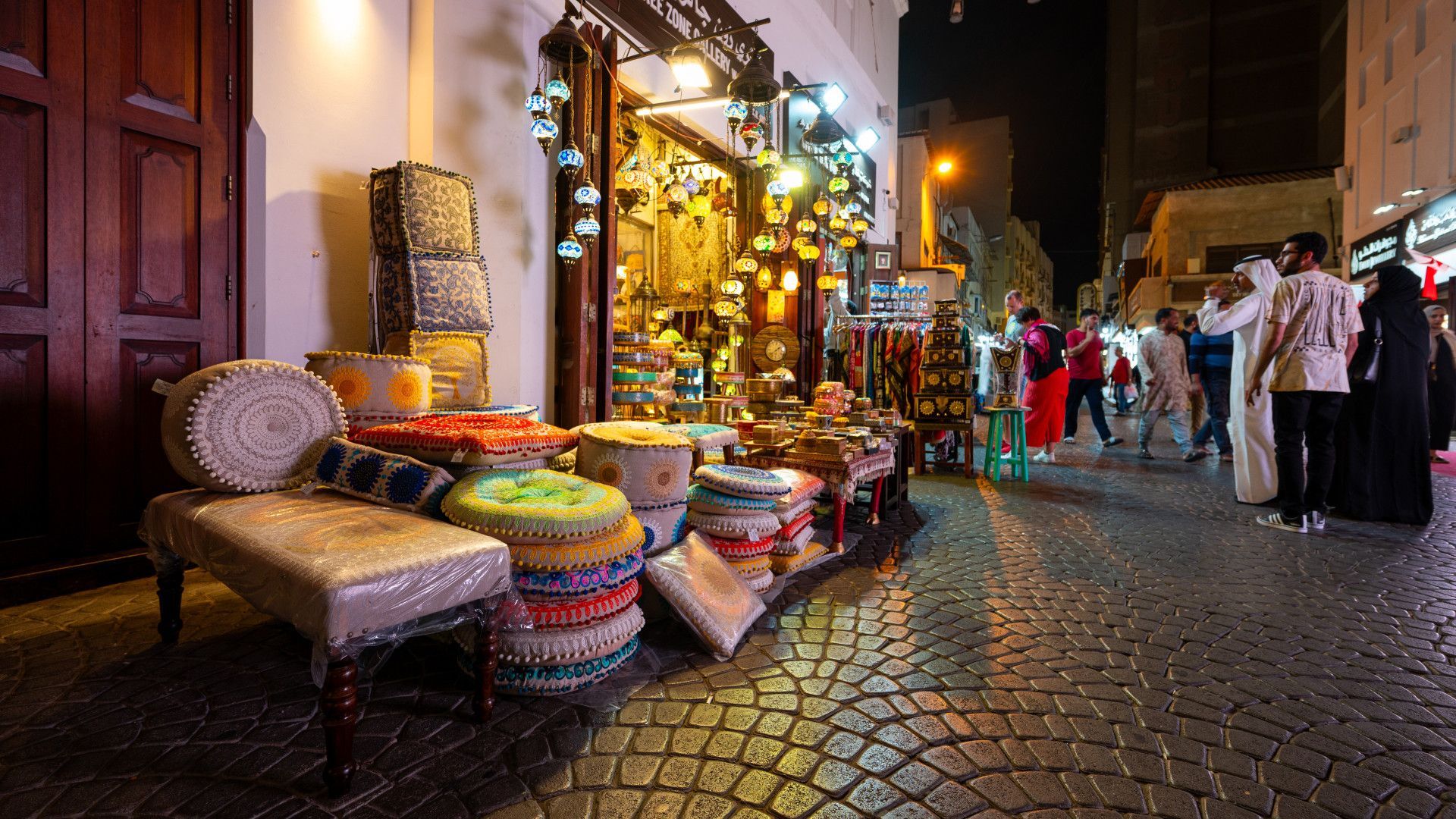 A group of people are walking down a cobblestone street in front of a store.