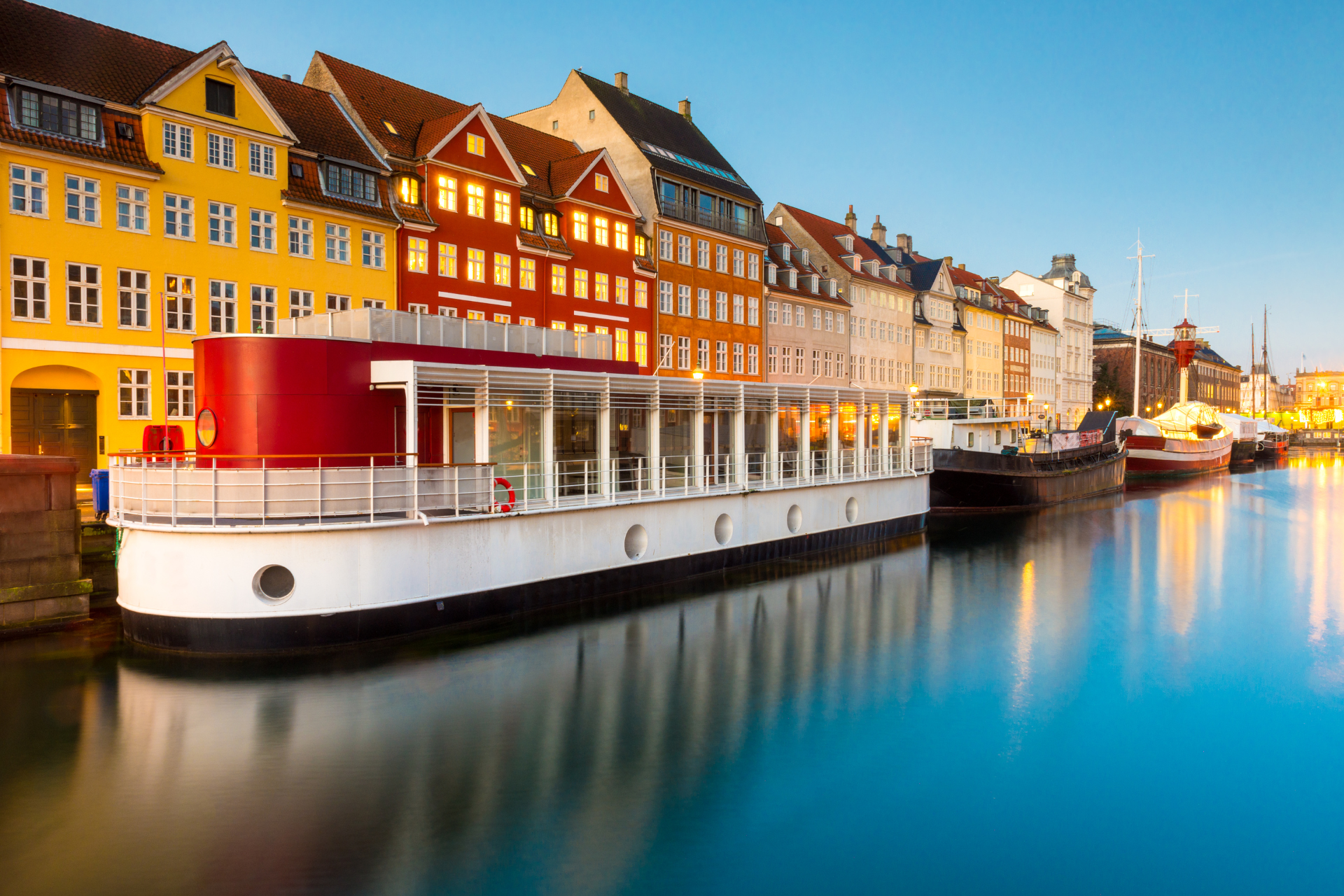 A boat is docked in the water in front of a row of buildings.