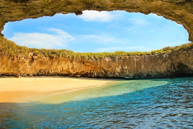 There is a cave in the middle of the ocean leading to a beach.