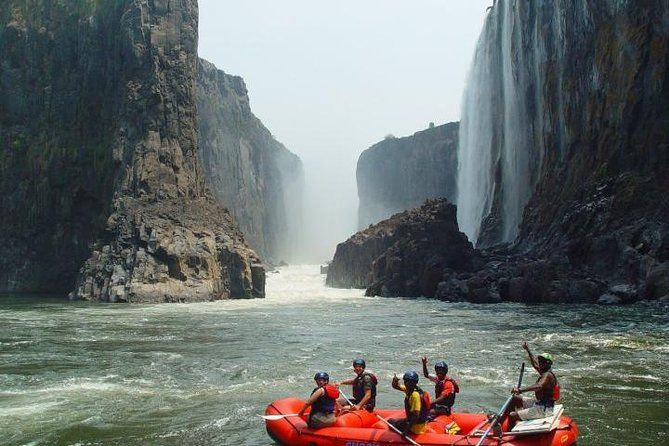 A group of people are rafting down a river near a waterfall.