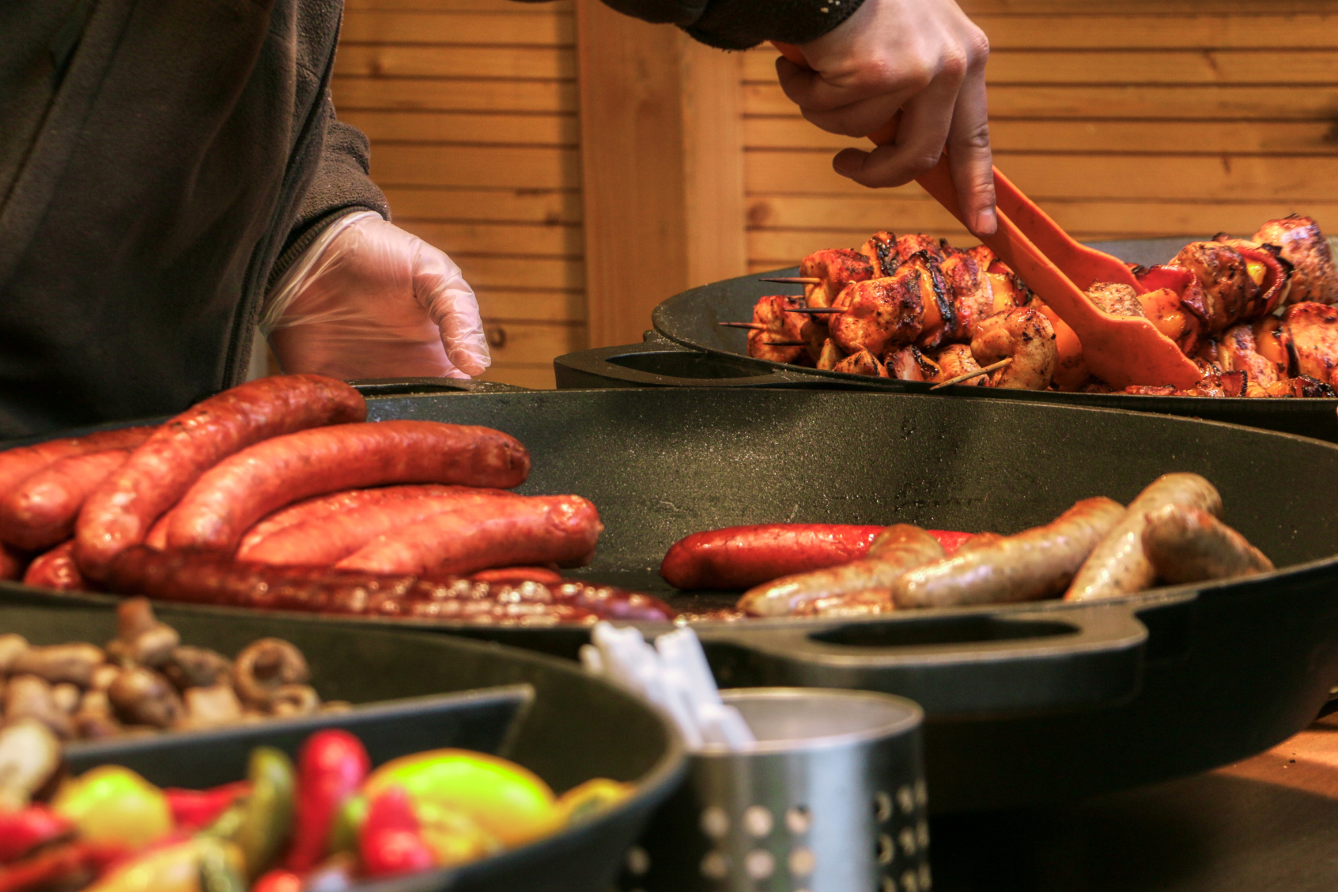 A person is cooking sausages in a pan with tongs