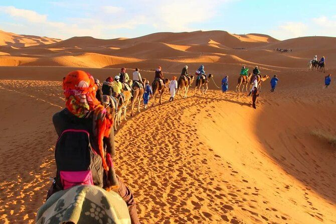 A group of people are riding camels through the desert.