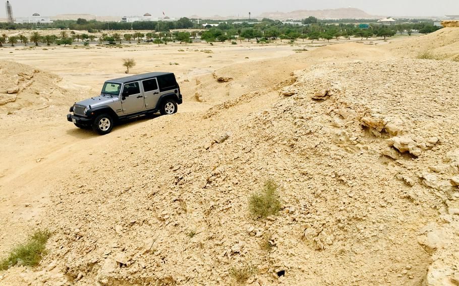 A jeep is driving down a dirt road in the desert