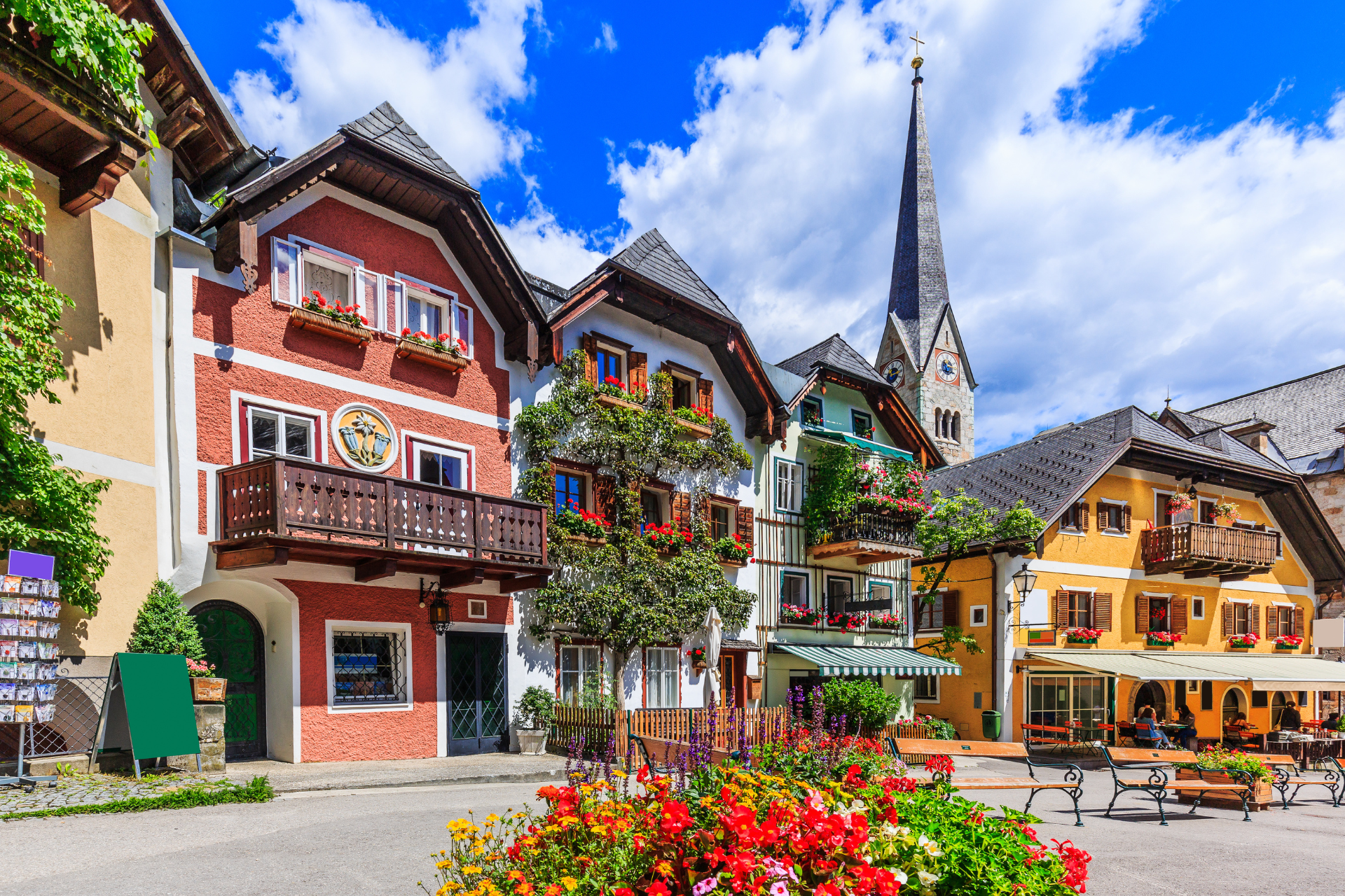 A row of houses with flowers in front of them and a church in the background.