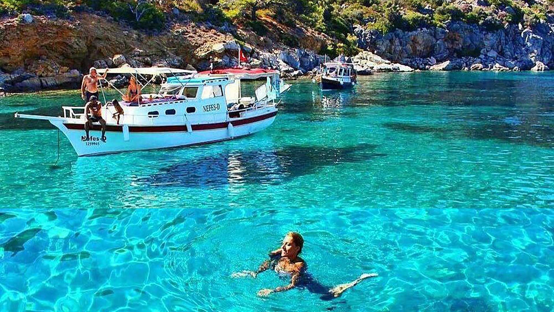 A woman is swimming in the ocean next to a boat.