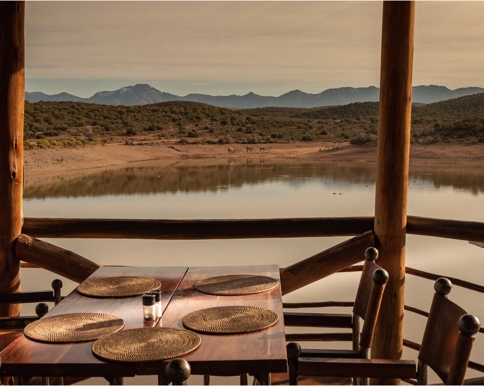 A table and chairs on a balcony overlooking a lake