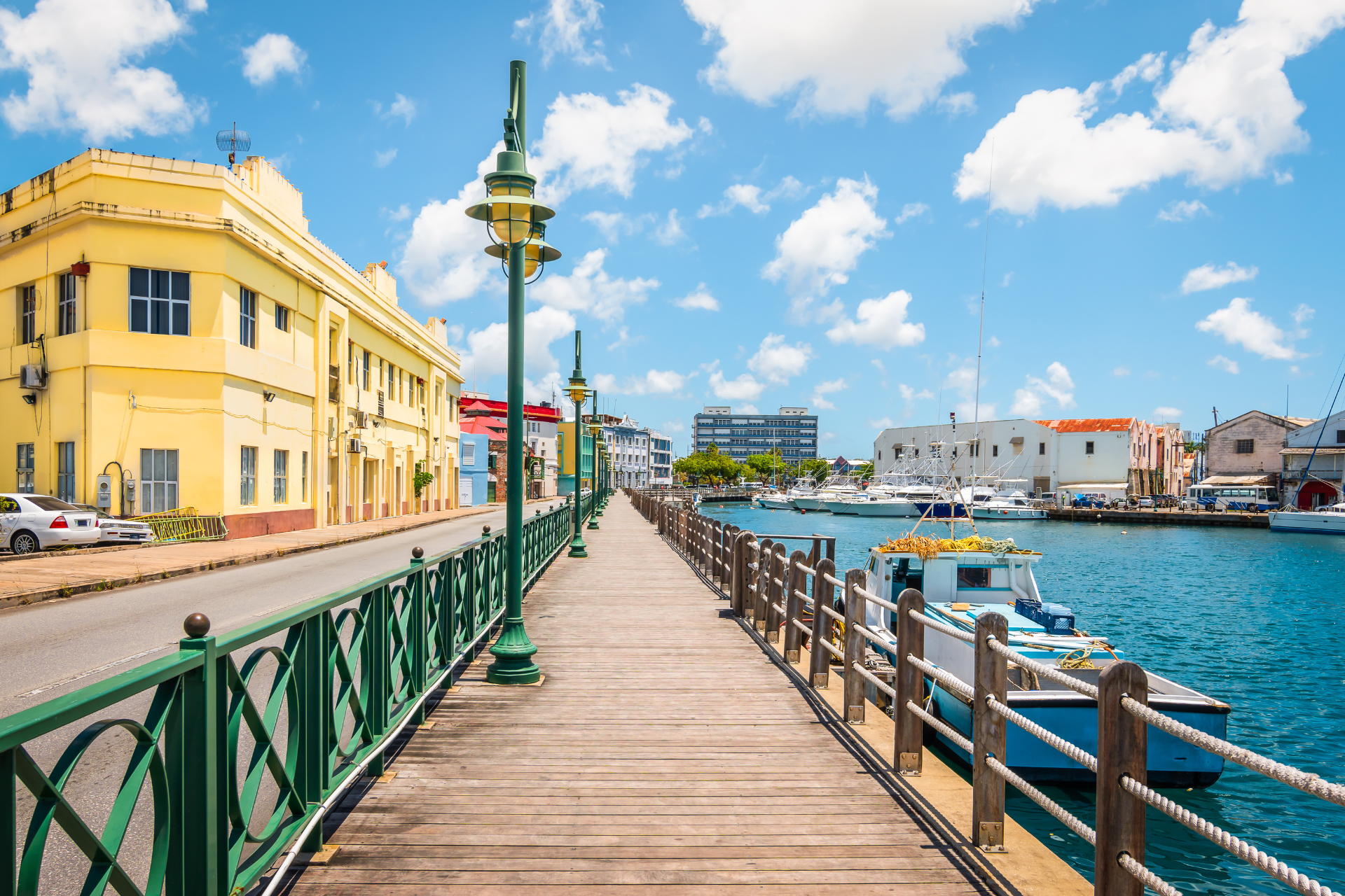 A wooden walkway leading to a body of water with a yellow building in the background.