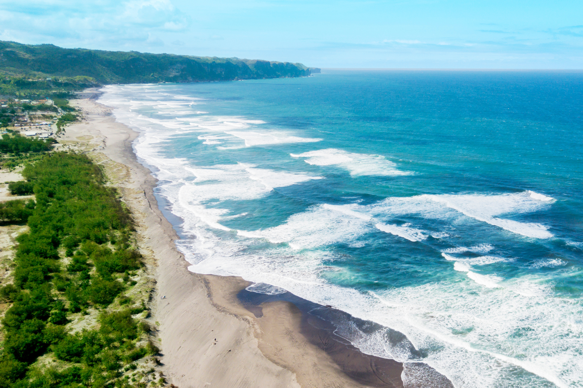 An aerial view of a beach with waves crashing on the shore.