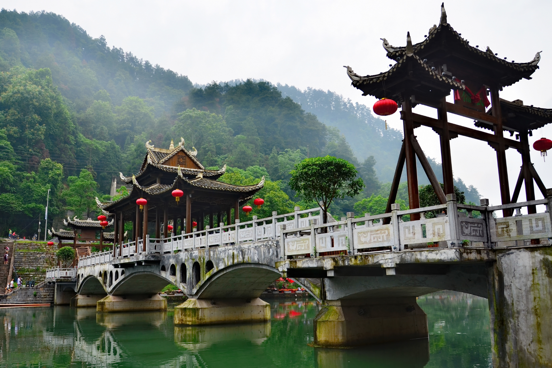 A bridge over a body of water with a pagoda in the background.