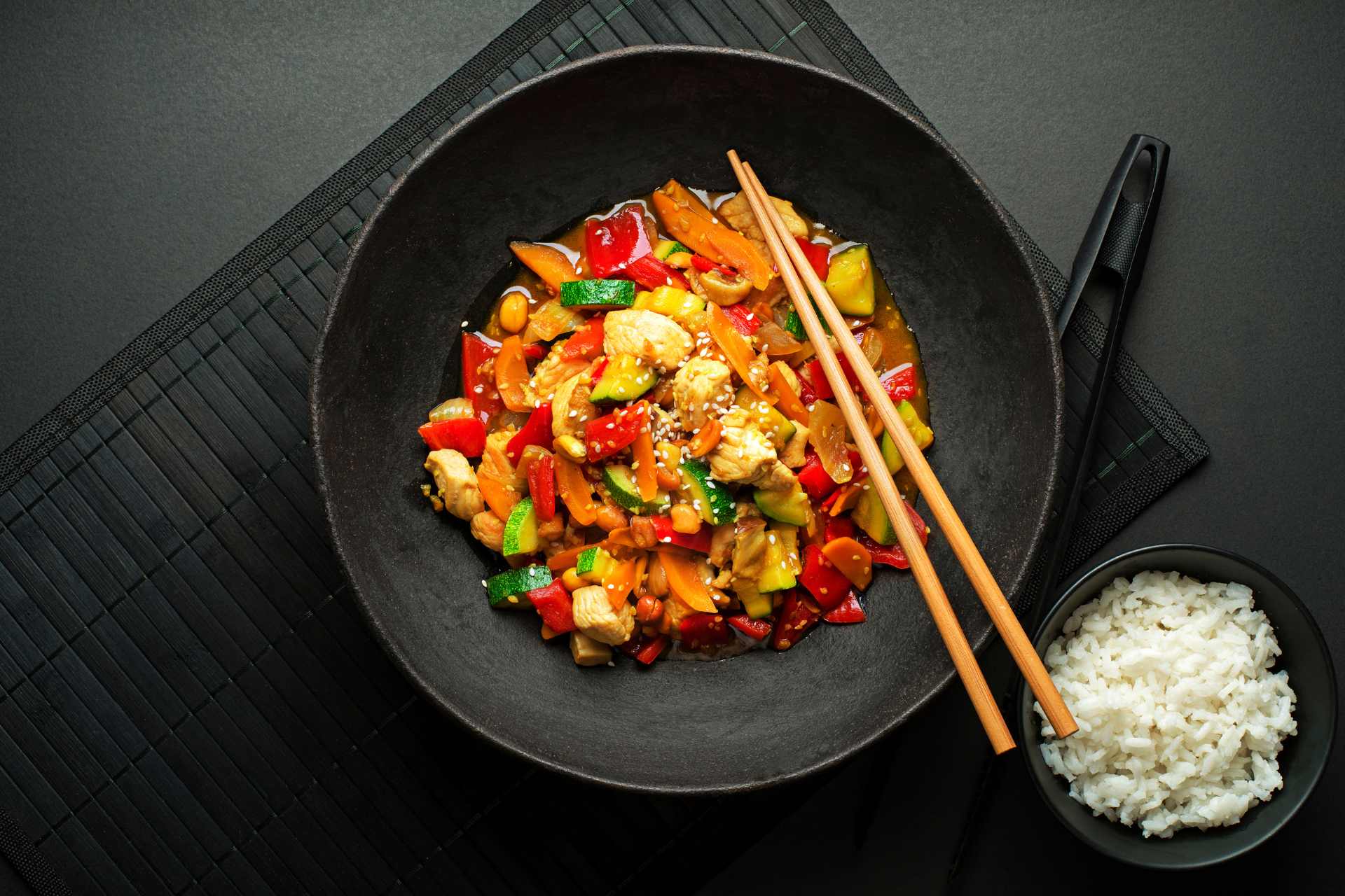 A bowl of food with chopsticks and rice on a table.