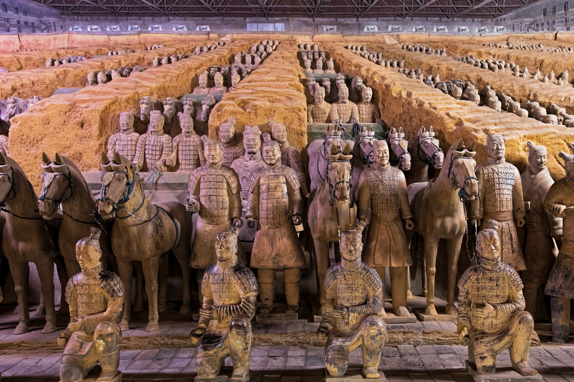 A large group of statues of soldiers and horses are lined up in a row.