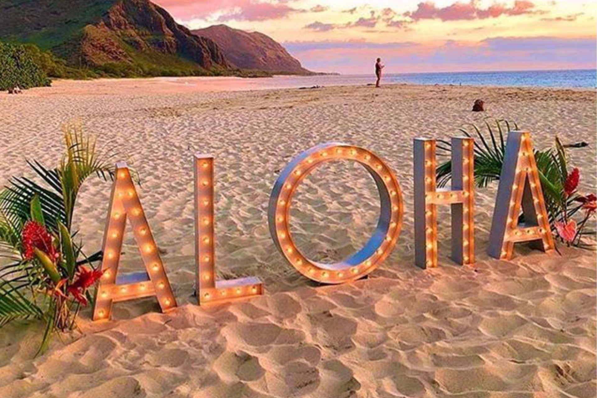 The word aloha is written in lights on the beach.