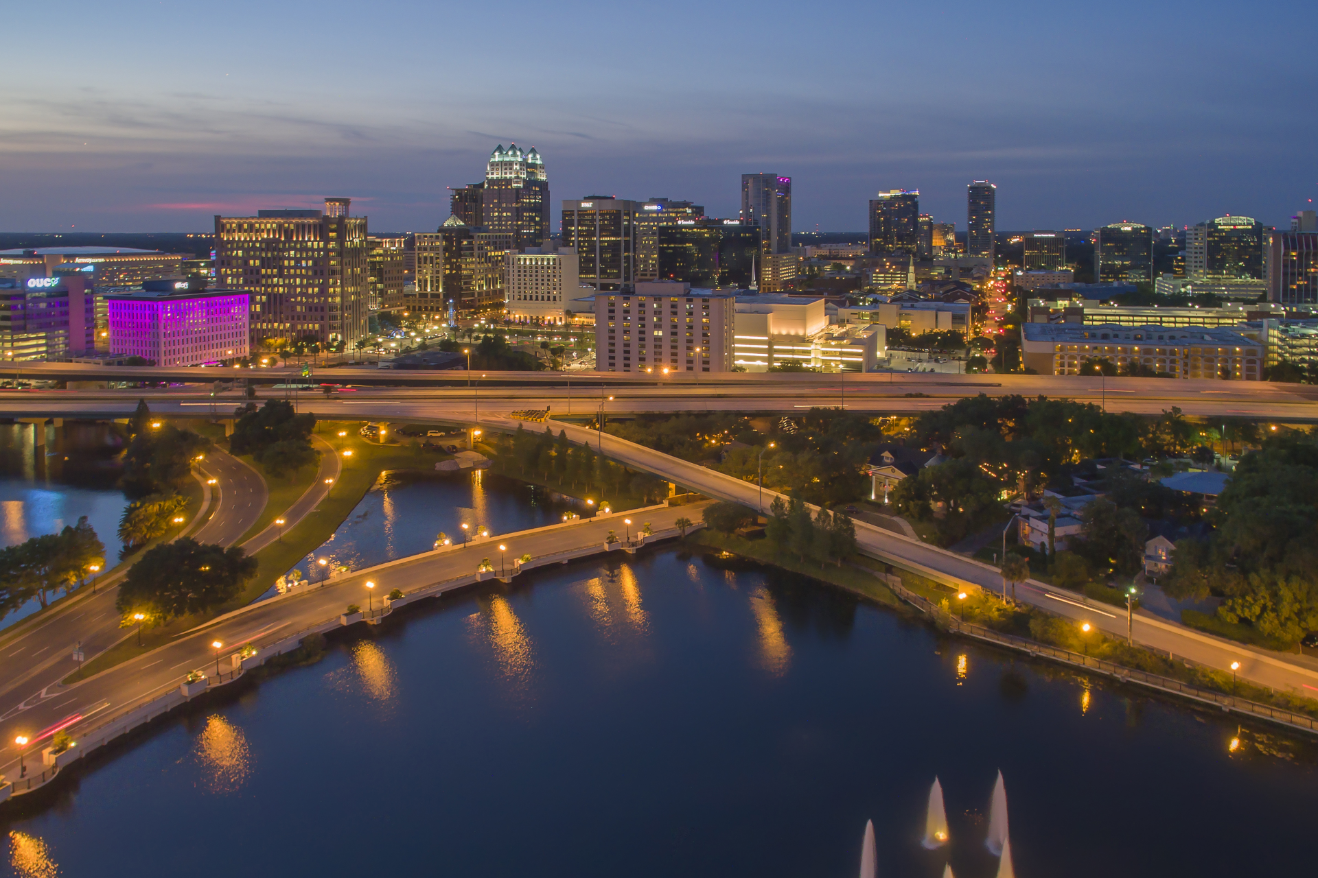 An aerial view of a city at night with a bridge over a river.