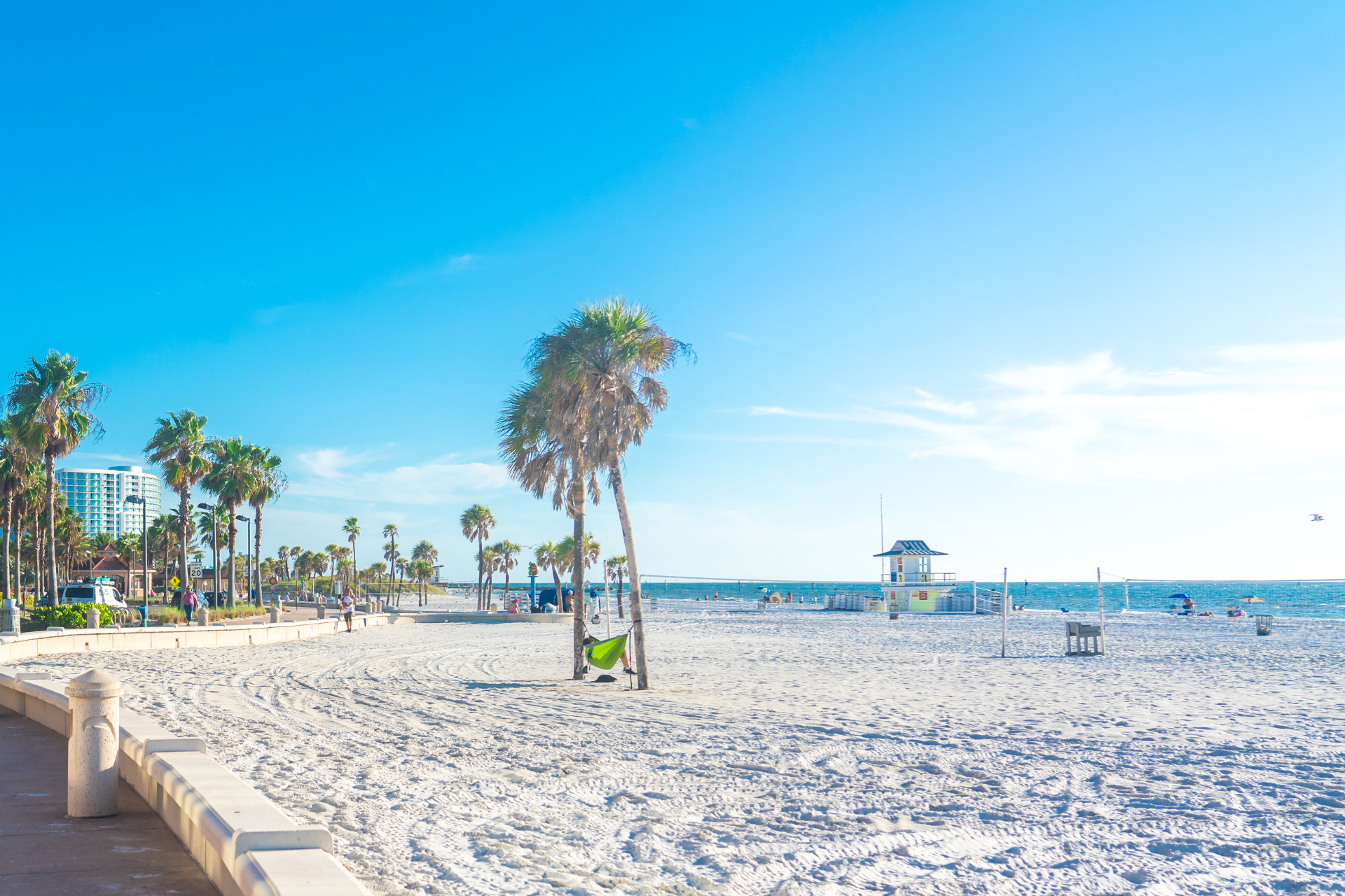 A beach with palm trees and a lifeguard tower on a sunny day.