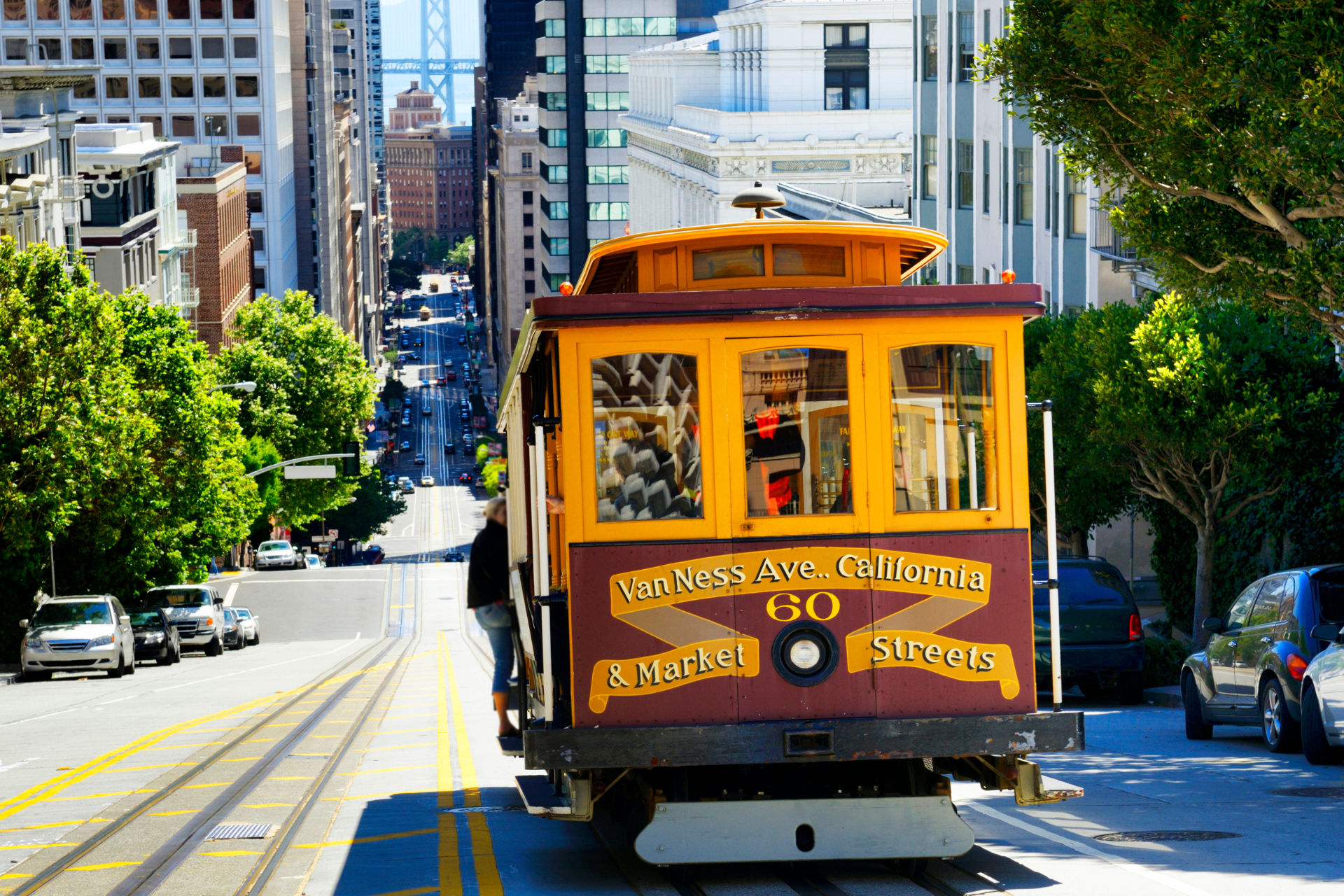 A yellow trolley is going down a city street