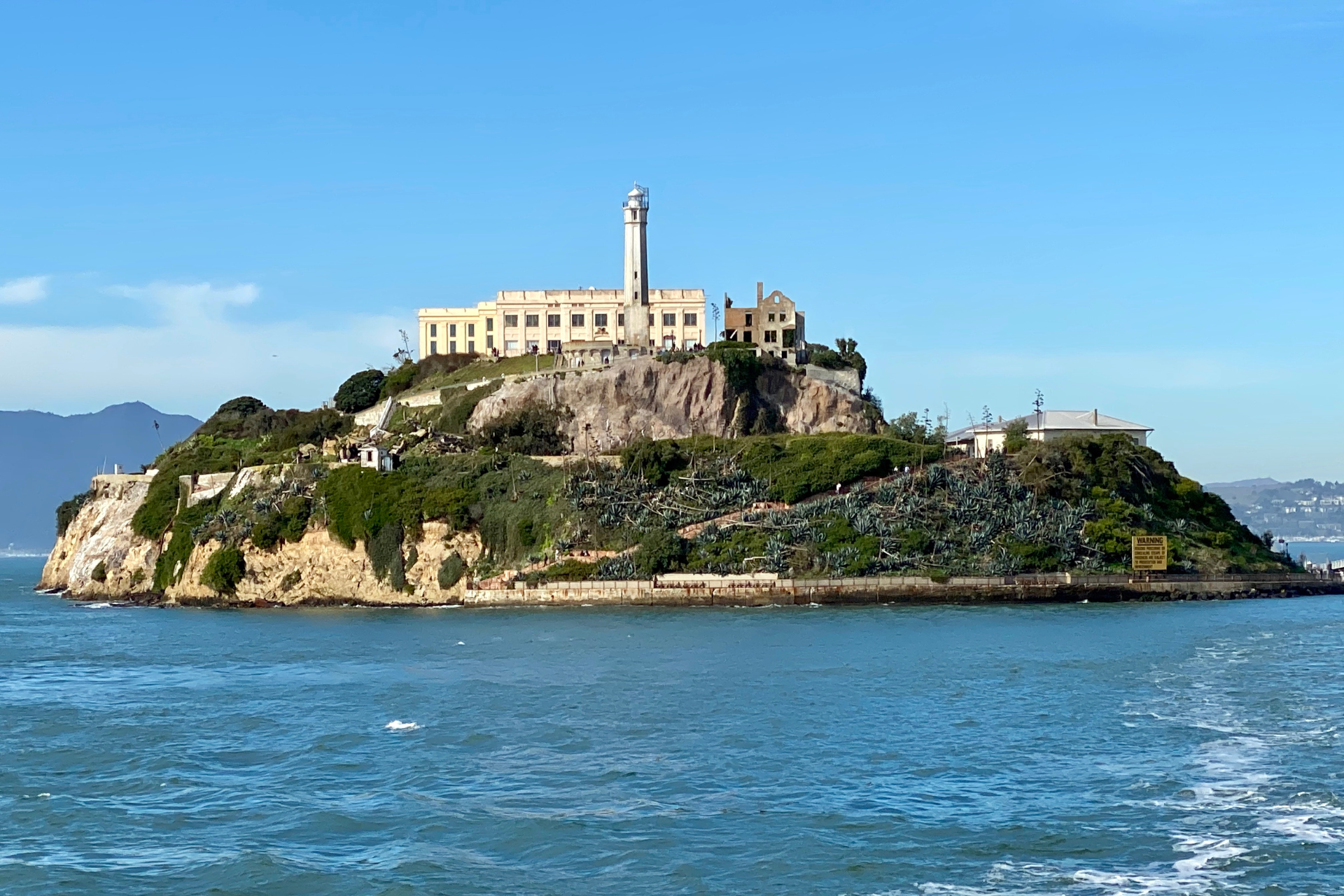 A small island in the middle of the ocean with a lighthouse on top of it.