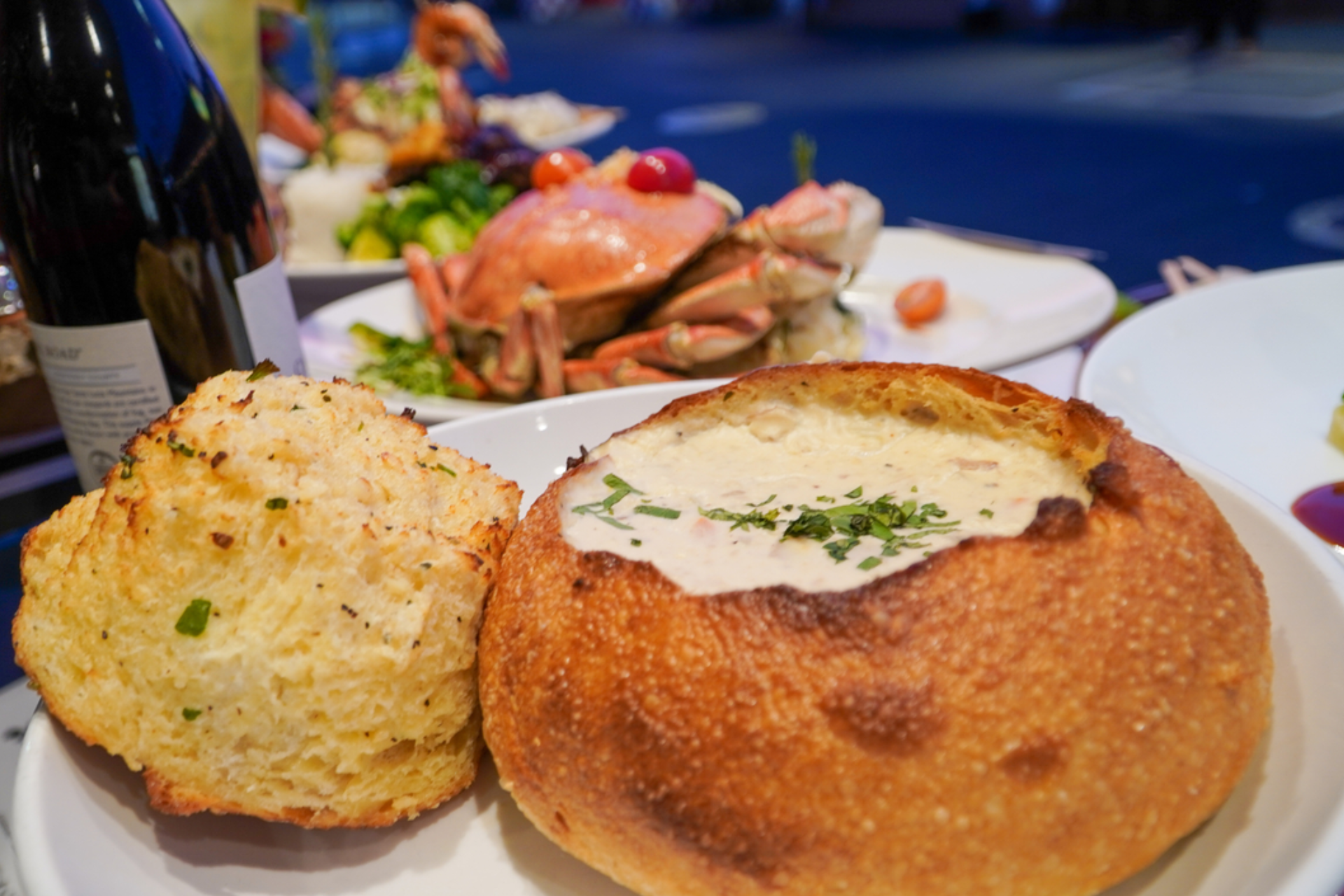 A bowl of soup and a biscuit on a plate.