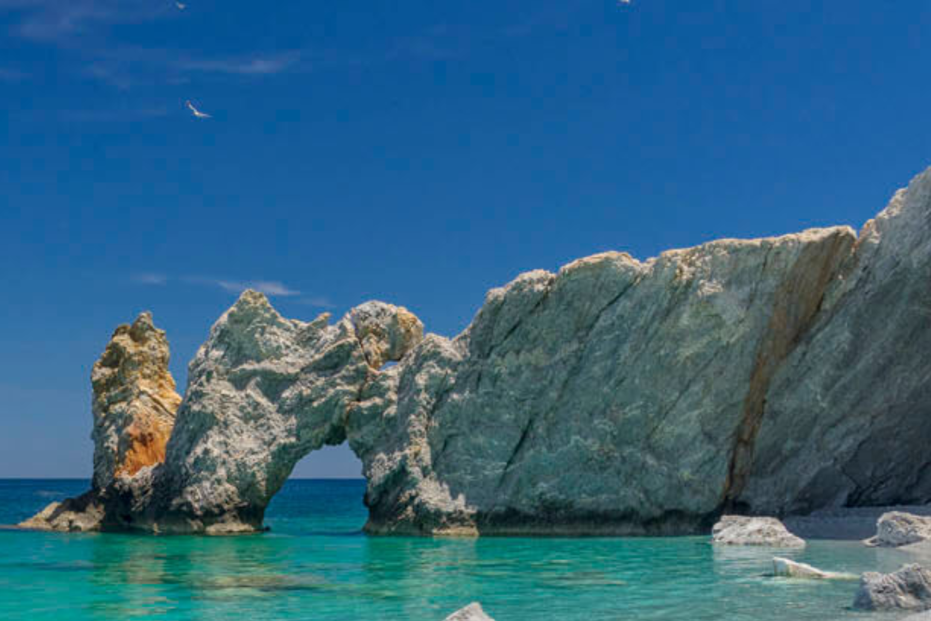 There is a large rock formation in the middle of the ocean.