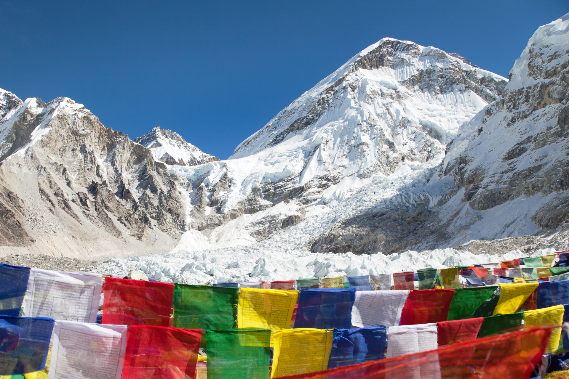 A row of colorful flags in front of a snowy mountain