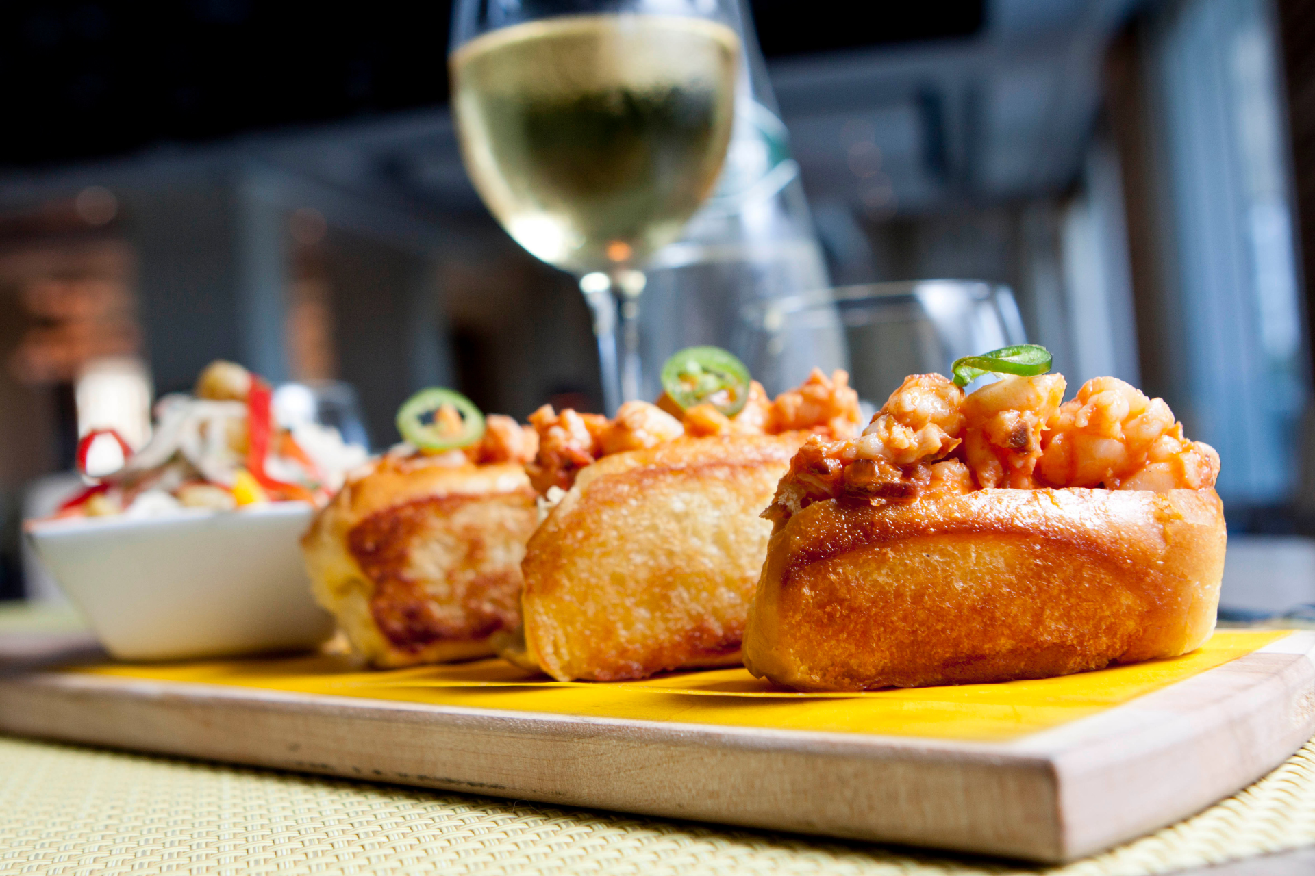 A cutting board topped with food and a glass of wine.