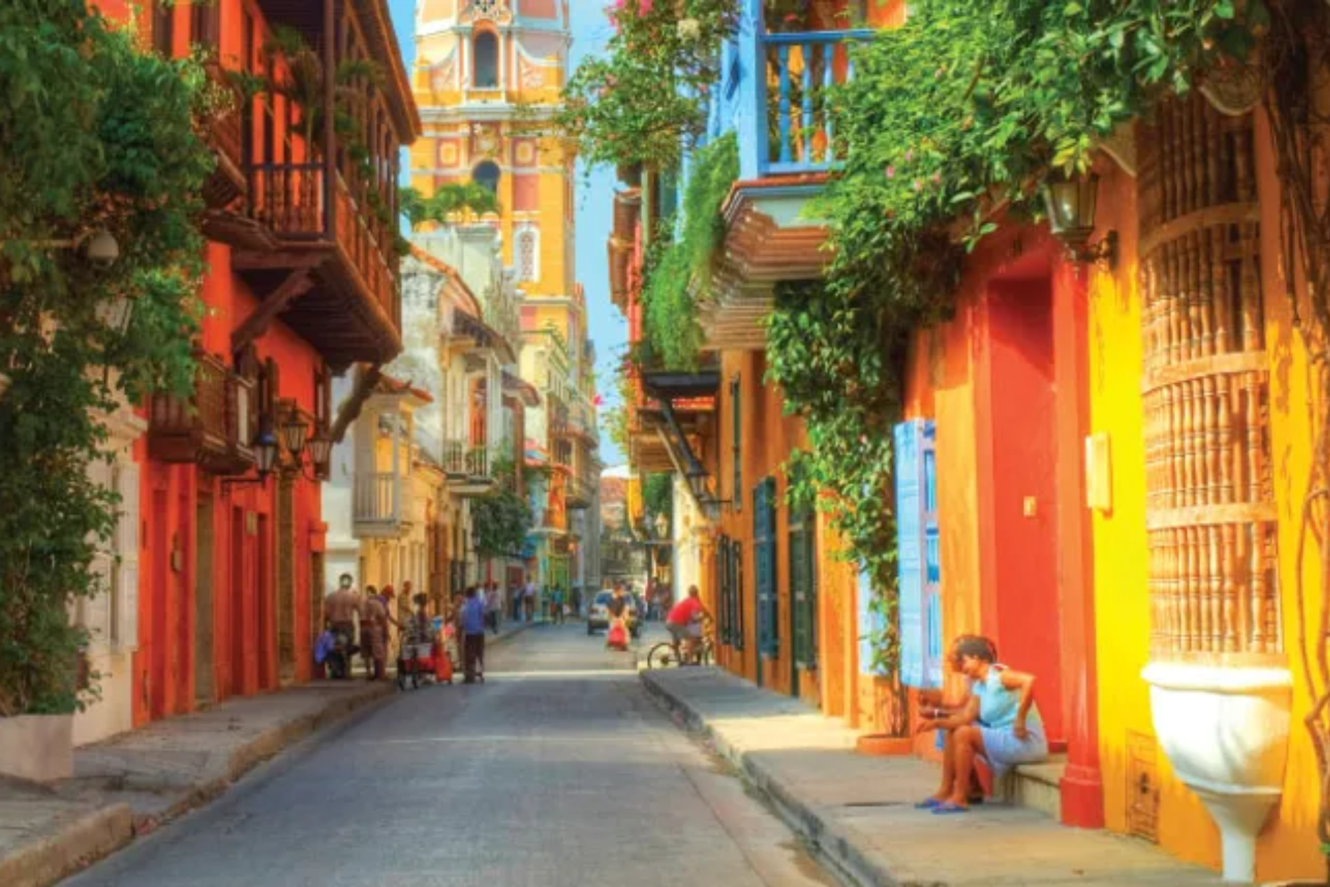 A woman is sitting on a bench in the middle of a narrow street.