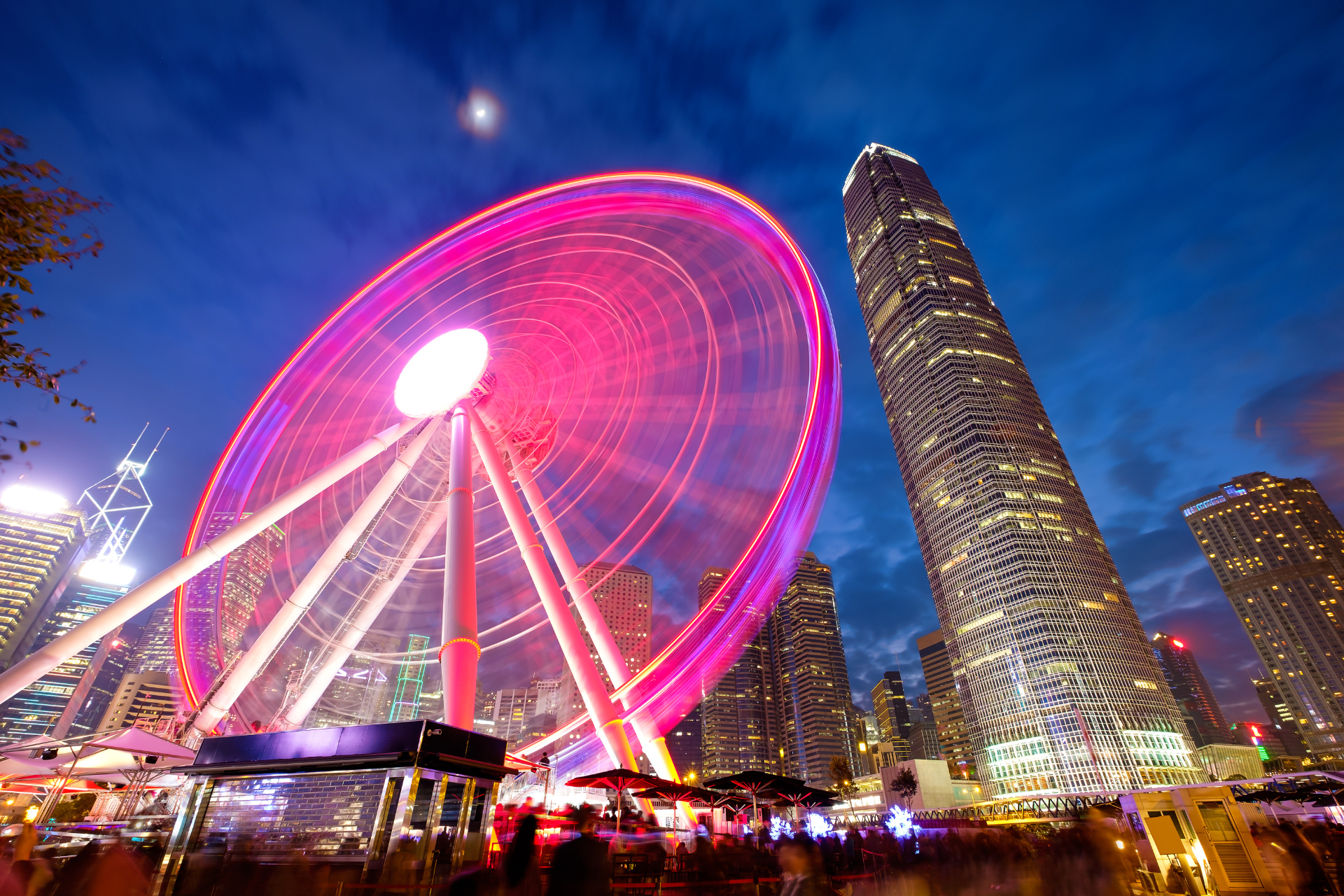 A ferris wheel is lit up in the middle of a city at night.