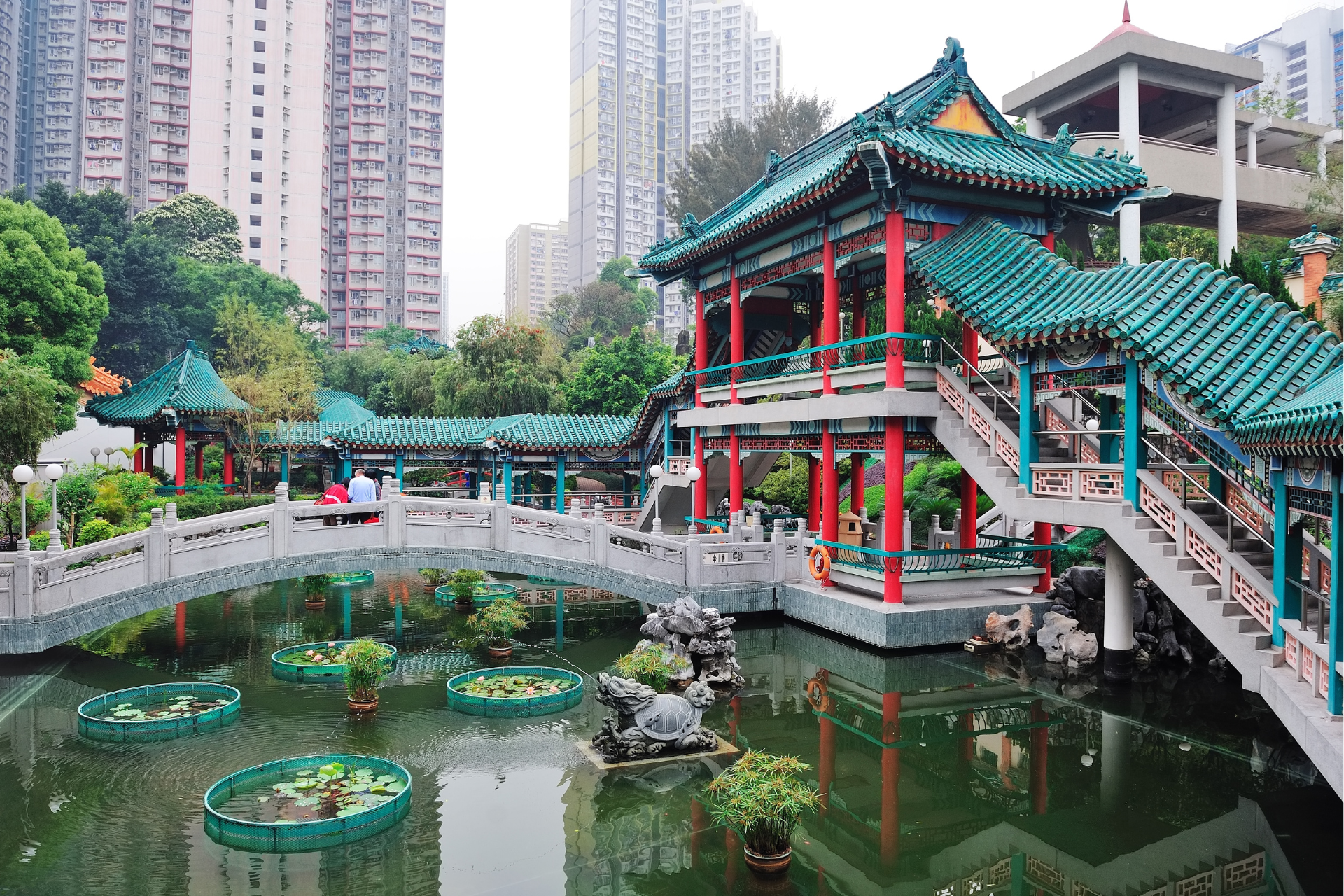 A bridge over a pond with a building in the background