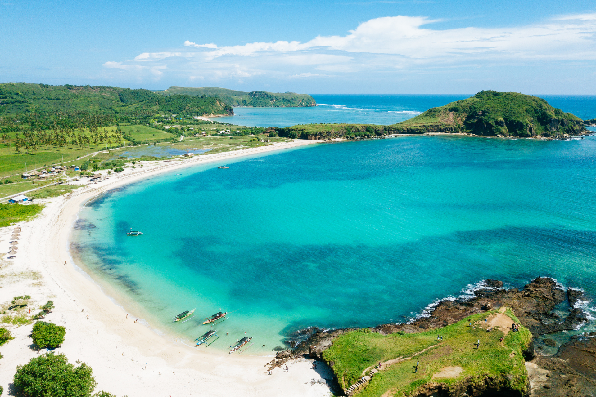 An aerial view of a beach with a large body of water and a small island in the distance.