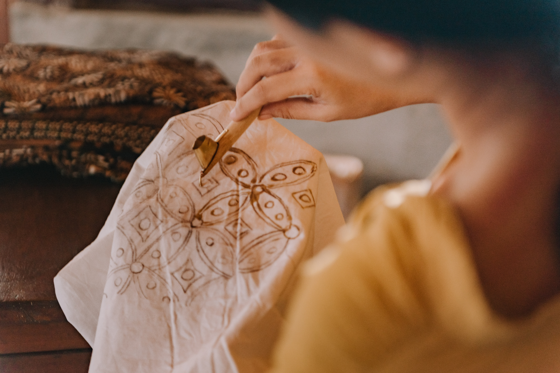 A woman is painting a butterfly on a piece of fabric.