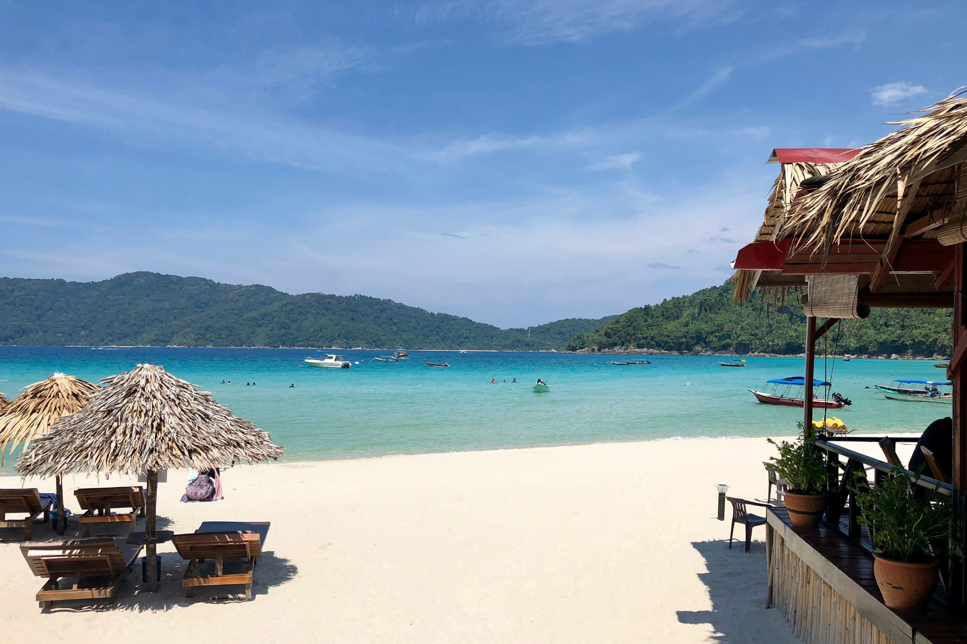 A beach with chairs and umbrellas and boats in the water