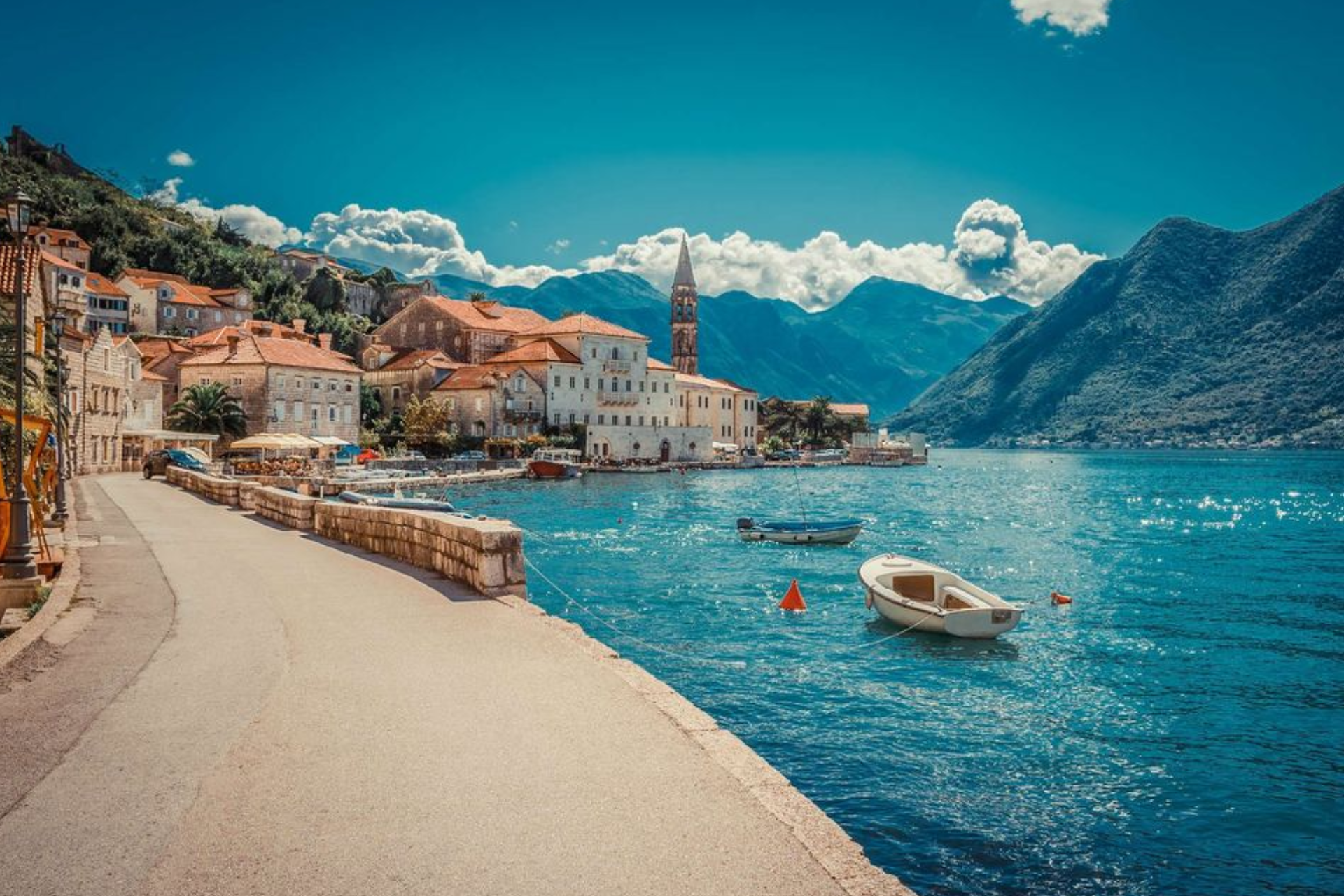 There are many boats in the water and a small town in the background.