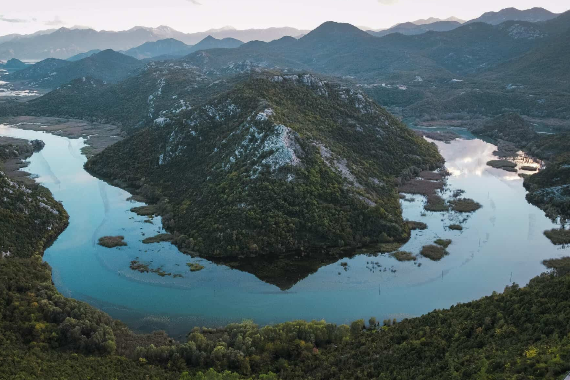 An aerial view of a lake surrounded by mountains and trees.