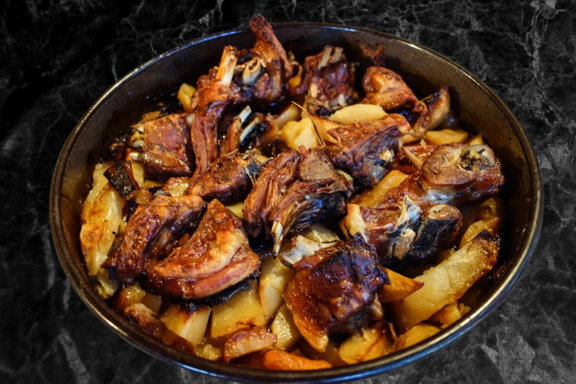 A pan filled with meat and potatoes on a table.