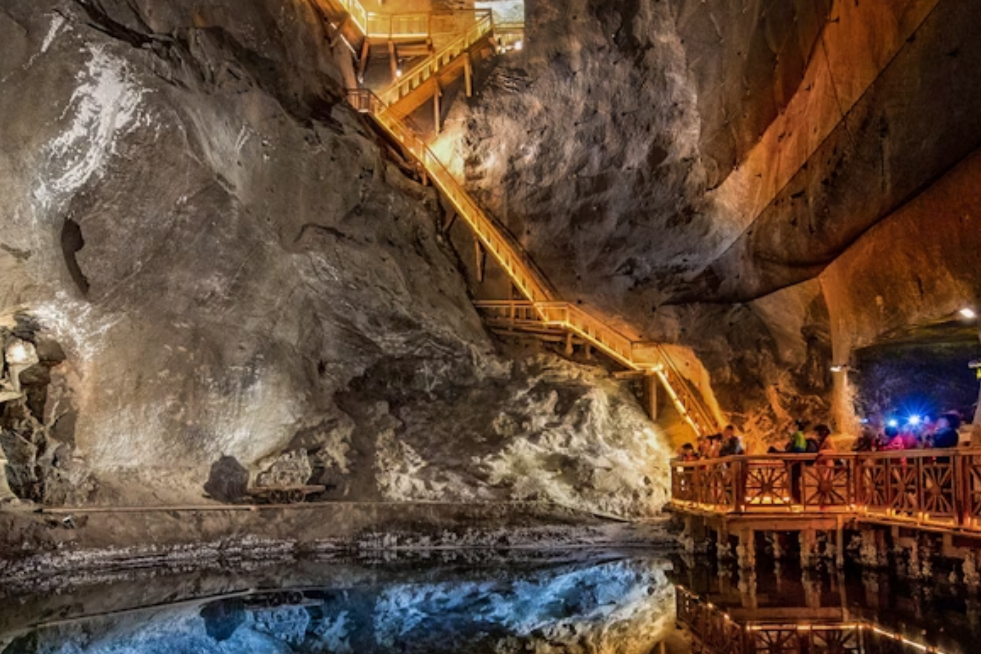 A group of people are standing on a bridge in a cave.