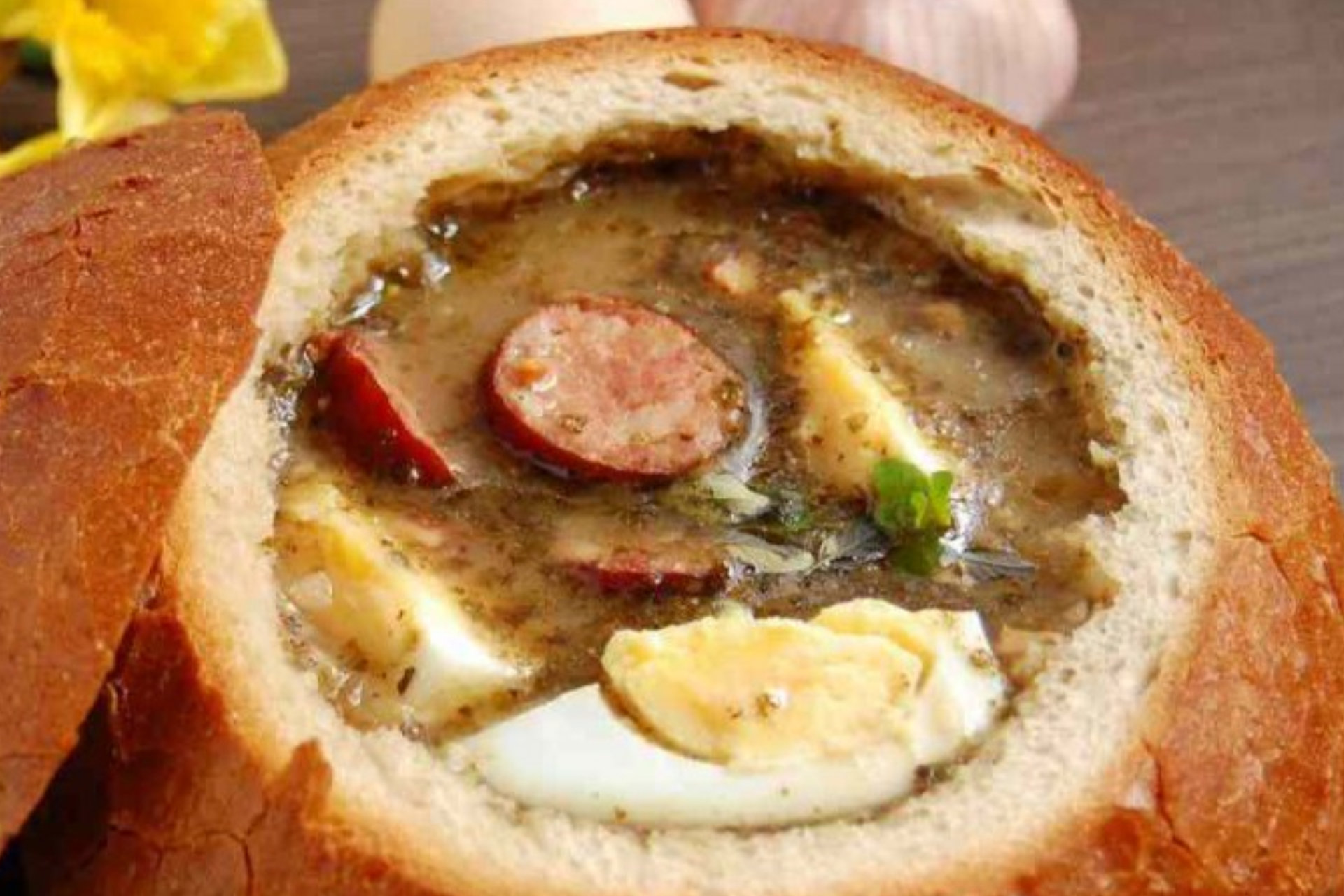 A close up of a bread bowl filled with soup and eggs.