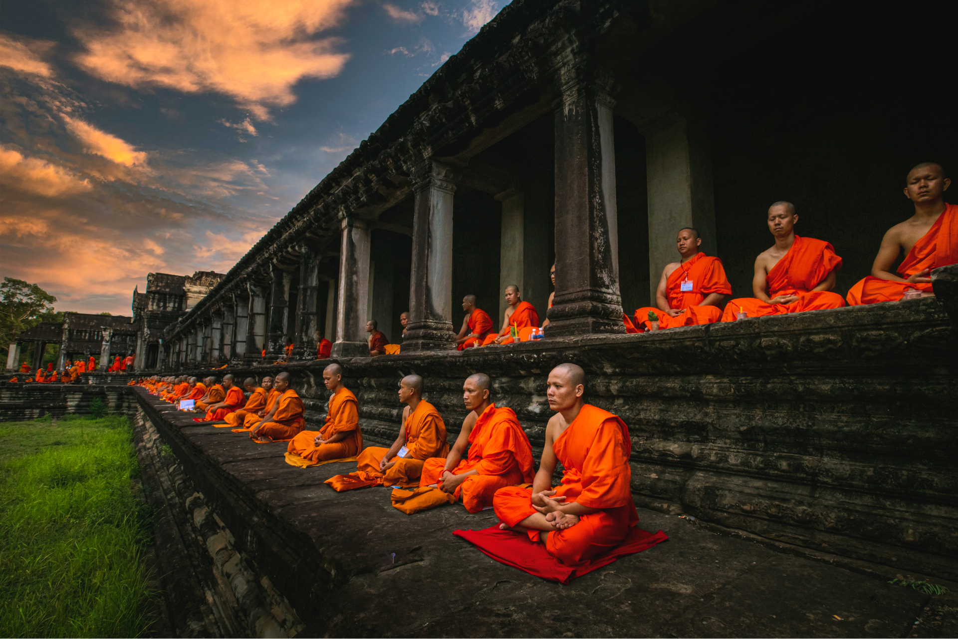 A group of monks are sitting on the steps of a building.