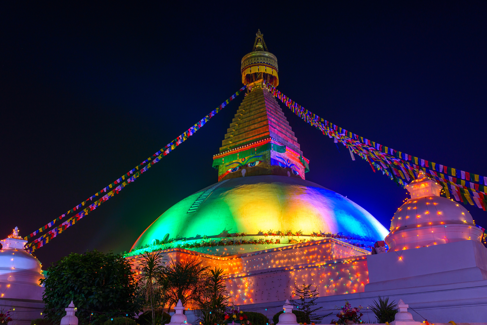 A temple is lit up with rainbow lights at night.